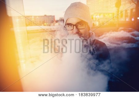 vaping man holding a mod device. cloud of vapor. Vape. high contrast and monochrome color tone.