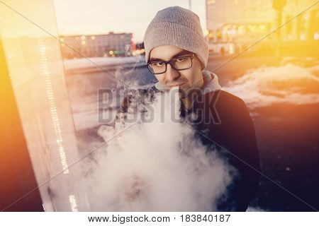 vaping man holding a mod device. cloud of vapor. Vape. high contrast and monochrome color tone.