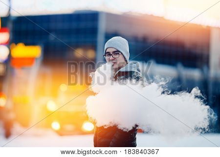 vaping man holding a mod device. cloud of vapor. Vape. high contrast and monochrome color tone.