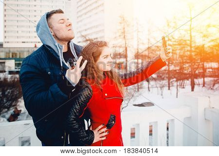 Vape guy and girl - lovers at sunset look in the phone and laugh. The concept of refusal of tobacco.Selfie