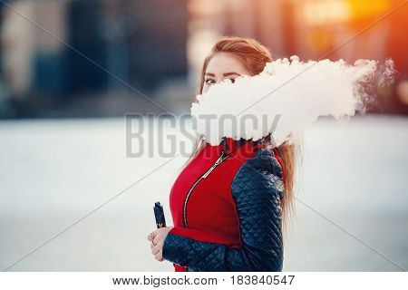 vaping girl holding a mod device. cloud of vapor. Vape