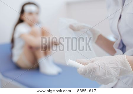 Wound treatment. Selective focus of bandage being held by a professional experienced nice doctor while preparing to treat the wound