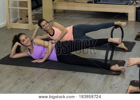 Portrait of two fit women exercising with pilates ring in gym