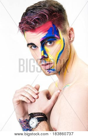 portrait of young attractive man with colored face paint on a white background. Professional Makeup Fashion. fantasy art makeup