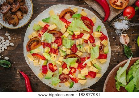 Tortilla With Salad Over It, Surrounded By Ingredients.