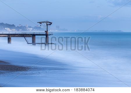 Beautiful seascape with tide and lonely pier with old crane
