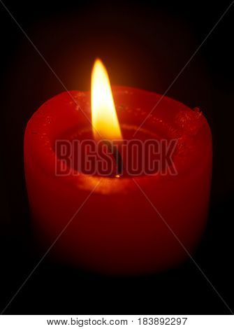 Burning red candle on black background close up