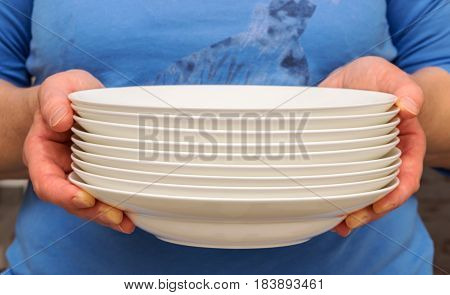 woman holding white plates in a kitchen