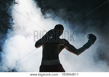 Afro american male boxer. Young man boxing workout in a fitness club. Muscular strong man on background black studio