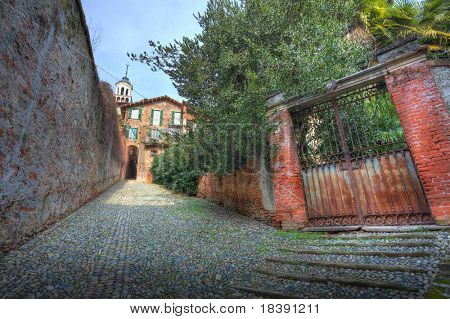 Alte rostige Tor und schmalen gepflasterten Straße in Stadt von Saluzzo, Norditalien.
