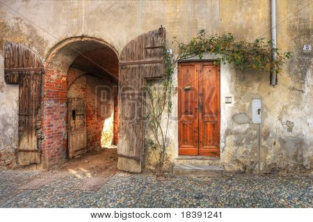 Hölzerne Tür und Tor Eingang zur Garage in alten Backsteinhaus in der Stadt von Saluzzo, Norditalien.