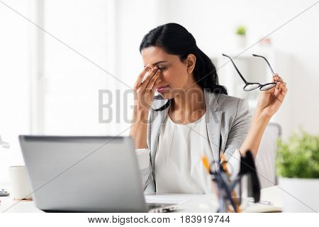 business, overwork, deadline, vision and people concept - tired businesswoman in glasses working at office and rubbing eyes