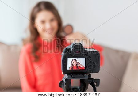 blogging, technology, videoblog, makeup and people concept - happy smiling woman or beauty blogger with bronzer and camera recording tutorial video at home