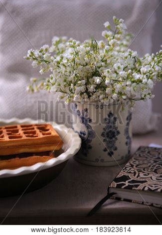 Still life with liège delicious waffles, notepad and white flowers in the Dutch porcelain vase