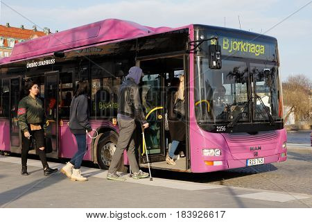 Orebro Sweden - April 4 2017:: Passengers boarding a violet city bus at the stop Jarntorget.