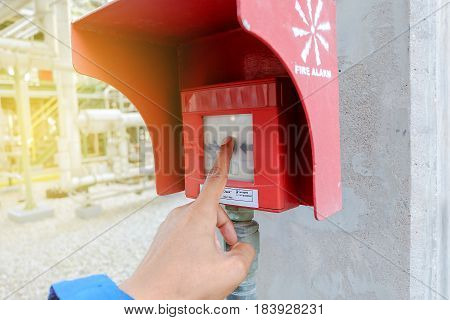 The hand of man is pulling fire alarm in petrochemical plant.