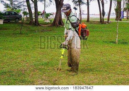 Labuan,Malaysia-April 29,2017:The worker of a garden cuts off a grass with grass cutter machine in Labuan,Malaysia on 29th April 2017.