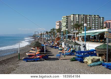 TORROX COSTA, SPAIN - OCTOBER 27, 2008 - Tourists relaxing on the beach with the promenade and apartments to the rear Torrox Costa Malaga Province Andalusia Spain Western Europe, October 27, 2008.