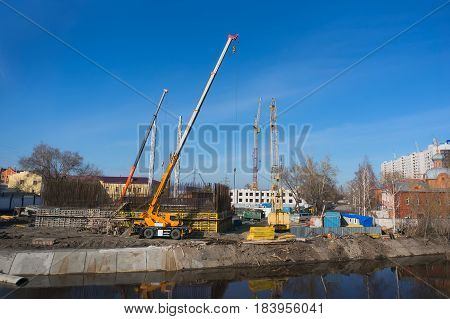 Construction of houses on the river Bank. A lot of tower cranes in the shot against the sky. The process of construction.