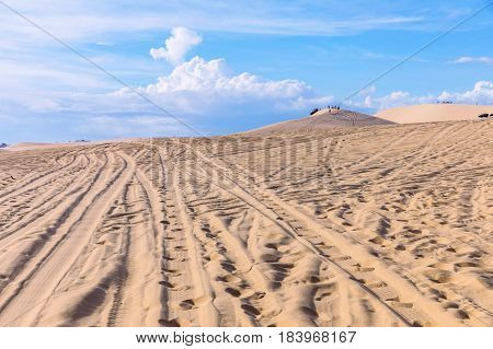 Sand dunes near Mui Ne. Group of off roads on top of dunes in the background. Sunny day with blue sky and clouds. Sand dune at Mui Ne Vietnam