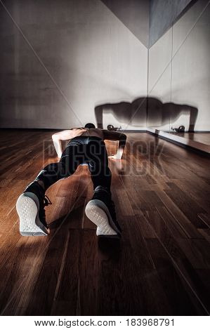 Attractive Muscular Man Doing Push-ups On A Wooden Floor.