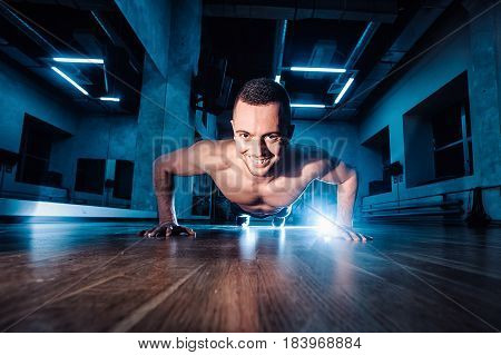 Attractive Muscular Man Doing Push-ups On A Wooden Floor.
