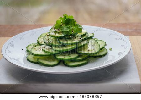 Fresh cucumber salad n a flat porcelain plate