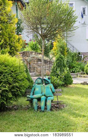 Schodnica Ukraine - June 30 2014: Decorative funny frogs sitting on bench in city park