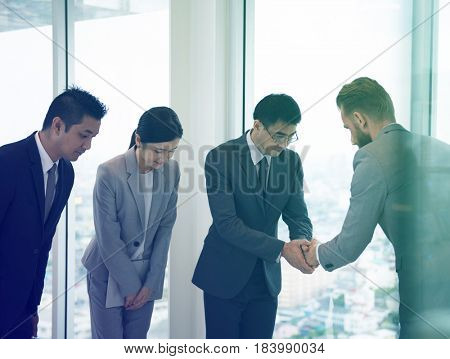 Business people greeting by handshake and take a bow