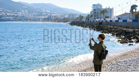 Female traveler taking a photo on the beach of Altea. Altea is the most beautiful place in the Costa Blanca. Spain