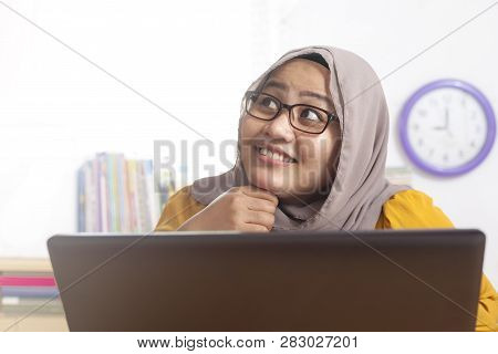 Portrait Of Asian Muslim Businesswoman Working On Laptop At The Office,amiling And Thinking Gesture,