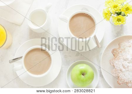 Breakfast On White Background. Tea Or Coffee With Milk, Apple Pie, Apple, Orange Juice And Yellow Fl