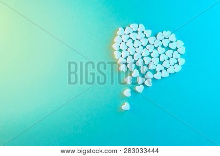 White Heart Shaped Candies On A Blue Paper Background. Dripping Heart Or Pearts Gethering Love Conce