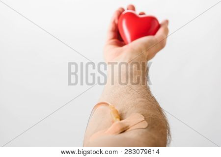 Partial View Of Blood Donor With Catheter And Plasters Holding Toy Heart, Blood Donation Concept