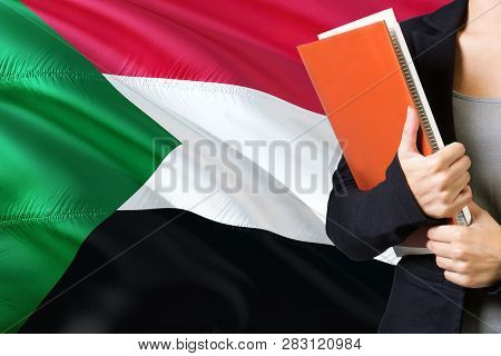 Learning Sudanese Language Concept. Young Woman Standing With The Sudan Flag In The Background. Teac