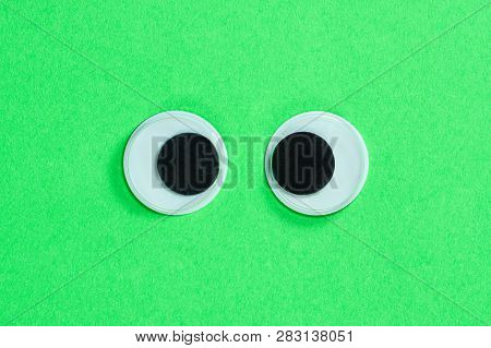 Cross-eyed Googly Eyes On Neon Green Background. Mad Funny Toys Eyes Close Up.