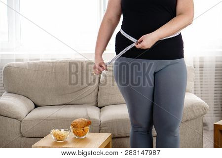 Imbalanced Nutrition, Weight Gain, Dieting. Overweight Woman With French Fries, Chips And Measuring 