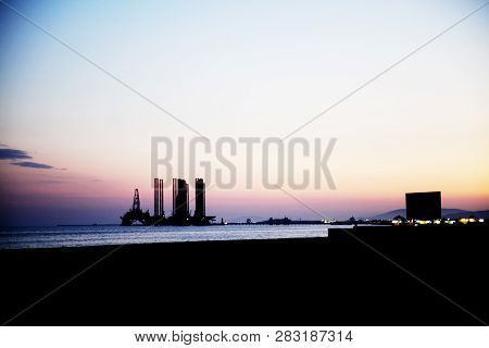 Silhouette Of Bridge Connected Offshore Oil Production Platforms At Oil Field During Sunset.