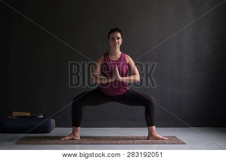 Beautiful Young Yoga Model Working Out Indoor Doing Goddess Or Sumo Squat Pose