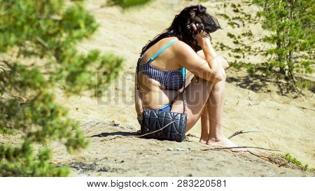Alone Sad Stylish  Woman Sitting On A Sea Beach, Talking On The Phone.  Lonely Woman  In A Bathing S