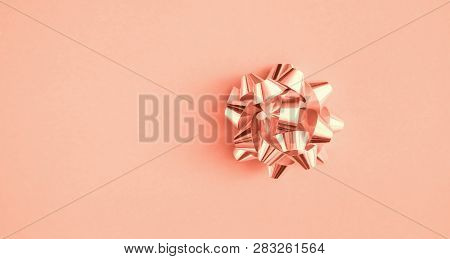 Coral Background. Metallic Bow Holiday Gift Decoration On Trendy Color Paper Texture Background. Top