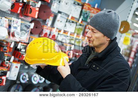 muž během nakupování, výběrem ochranná přilba stavební supermarket obchod dodávky hardware