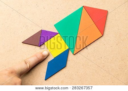 Color Tangram In Rocket Shape With Hand At The Base On Wood Background (concept For Startup, New Exp