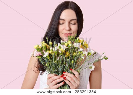 Beautiful Young Lady With Straight Long Hair, Smells Flowers With Pleasant Odour, Closes Eyes, Wears