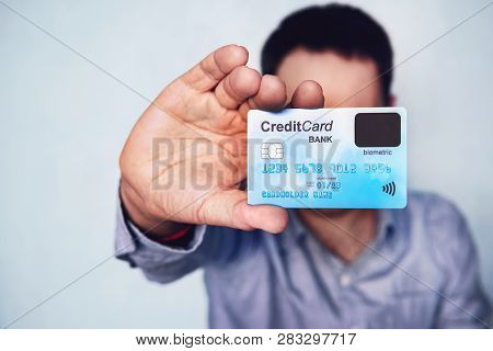 Concept Of Biometric Verification On Credit Card. Cardholder Showing Payment Card With Finger Sensor