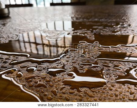 Color Image Of A Puddle Of Water And Rain Drops On A Wooden Platform.