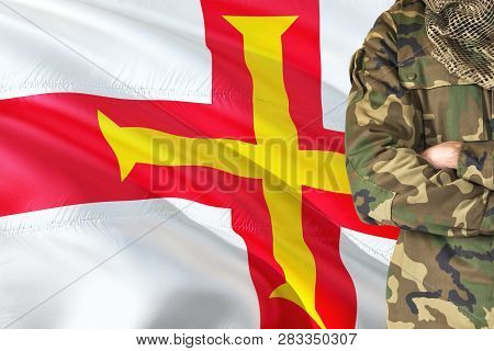 Crossed Arms Soldier With National Waving Flag On Background - Guernsey Military Theme.