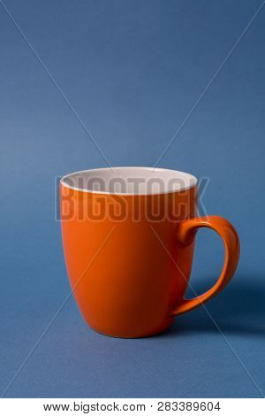 Big Orange Empty Mug Isolated On Blue Background, Vertical.