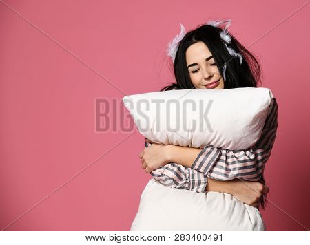Beautiful Brunette Girl Just Woke Up With Soft Pillow And Feathers. Woman Yawning Sleepy Day On Pink