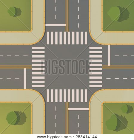 Crossroads Of Two Roads With Pedestrian Paths, Curbs And Boards, Road Markings, Grass, Bushes And Tr